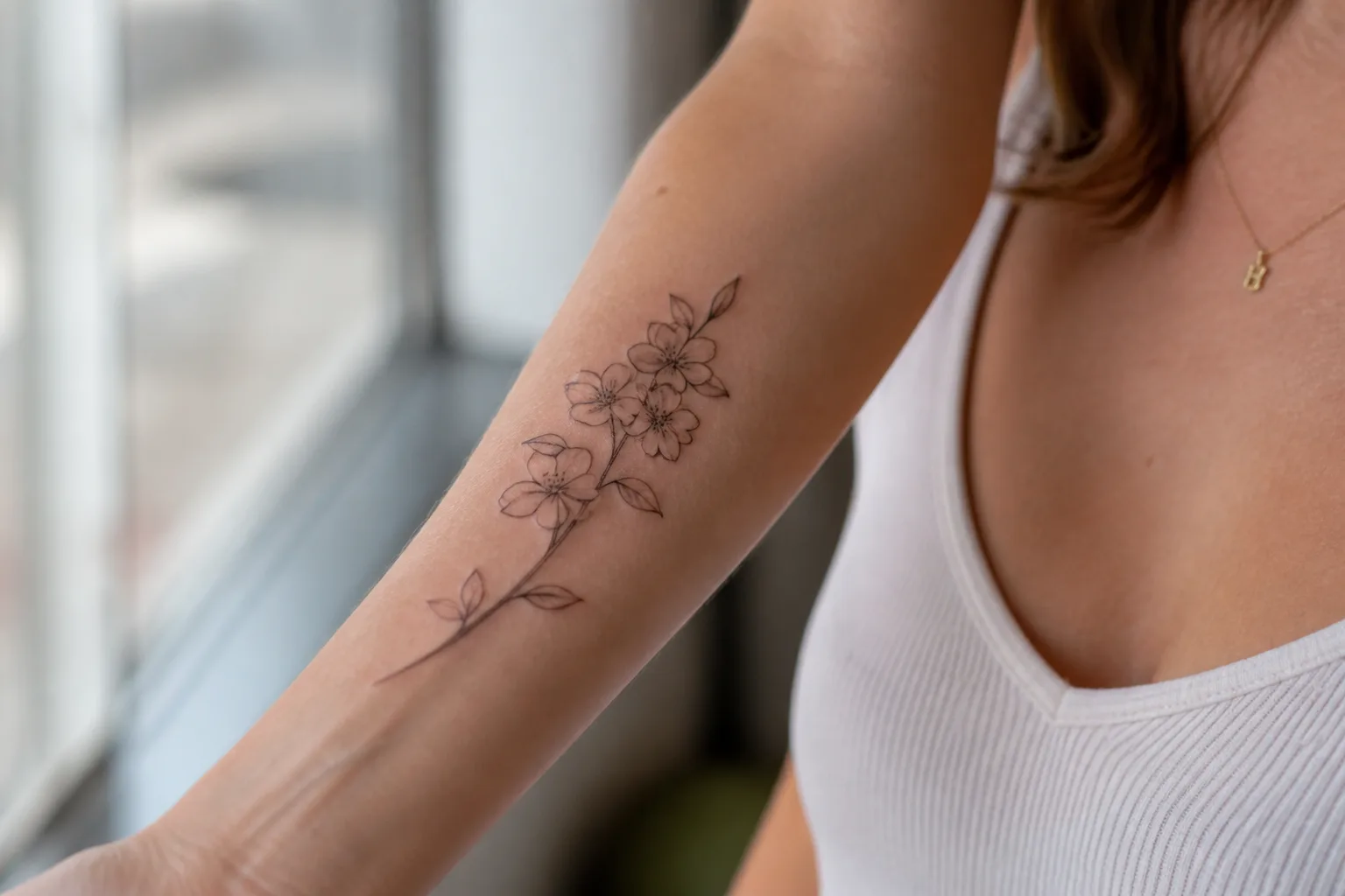 Fine-line floral tattoo on a forearm showing realistic placement and scale