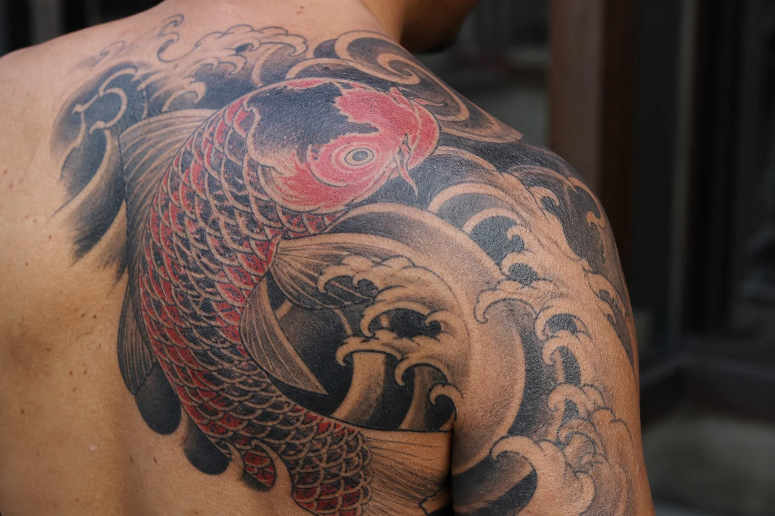 Japanese koi tattoo on upper back showing a large personalized concept on skin